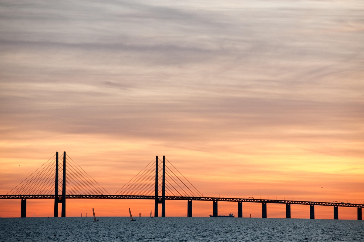 The sun is setting behind the bridge between Sweden and Denmark.